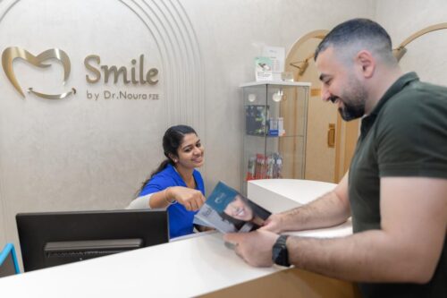 A receptionist assists a patient at Smile by Dr Noura, a trusted dental clinic in Dubai.