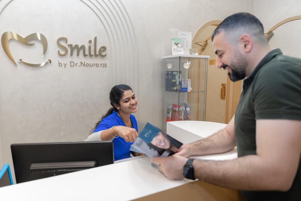 A receptionist assists a patient at Smile by Dr Noura, a trusted dental clinic in Dubai.